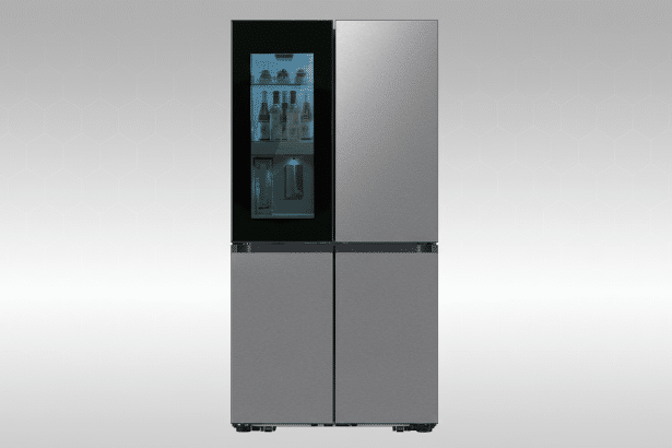 A modern, four-door stainless steel refrigerator with a transparent glass panel on the upper left door, revealing beverages inside. The appliance is set against a subtle gray and white patterned background. Filename : modern four doorre frigerator.png