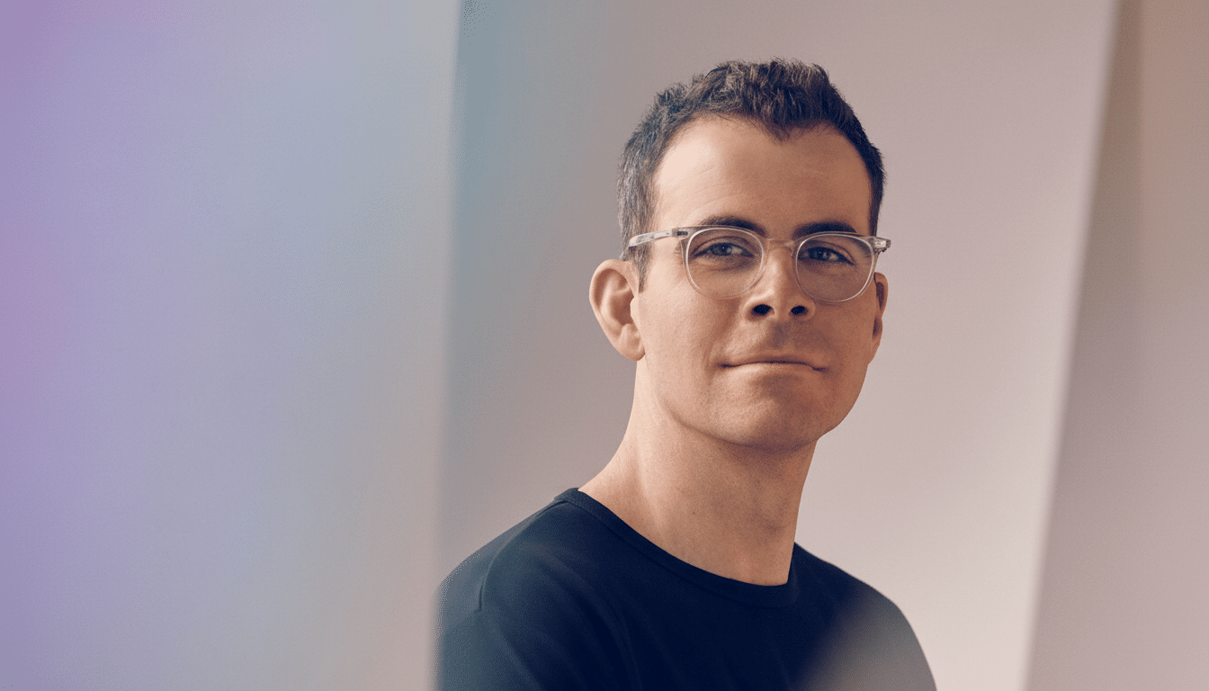 A man with short, dark hair and glasses looking directly at the camera , resized to a 1 6:9 aspect ratio with the original background maintained .