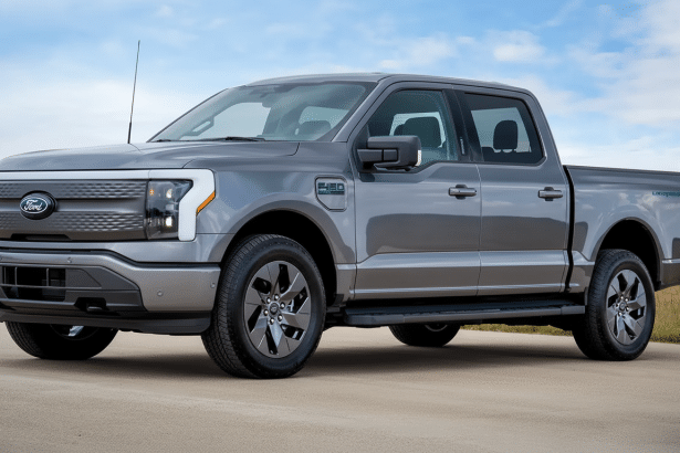 A gray Ford F-15 0 Lightning electric pickup truck parked on asphalt under a partly cloudy sky.