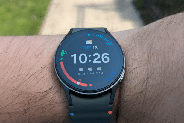 A close -up shot of a smartwatch on a persons wrist, displaying the time 10: 2 6, date Tuesday 1 6, and weather information.