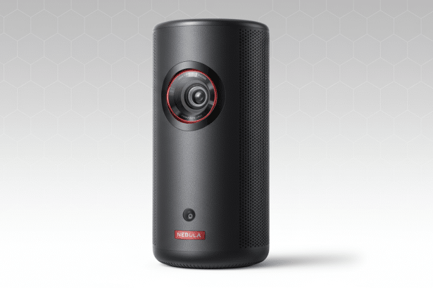 A black Nebula portable projector is centered against a soft gray and white background with a subtle hexagonal pattern. The device features a prominent lens with a red ring and a NEBULA logo at the bottom .