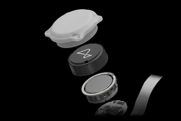 An exploded view of a small, round electronic device, showing its internal components including a white casing , a black central unit with a symbol, a metallic battery or sensor, and a circuit board, all against a dark background.