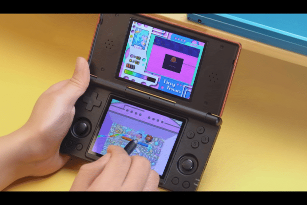 A person playing a Nintendo DS , with a close -up of their hands on the device and a game displayed on both screens.