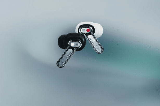 Two Nothing Ear ( 1) earbuds, one black and one white, are shown on a soft , light gray and teal gradient background. Filename : nothingear 1ear budsprofessional .png