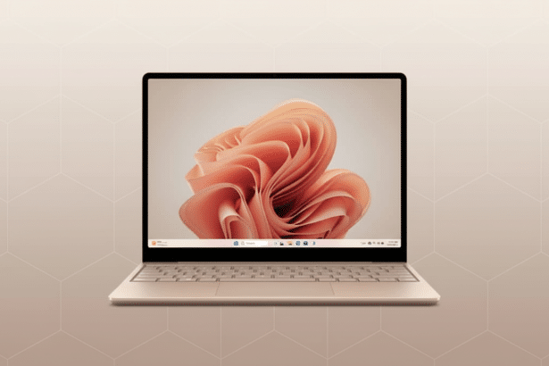 A champagne -colored laptop with a light pink, abstract floral wallpaper on the screen, set against a soft, geometric patterned background.