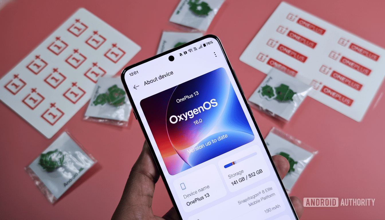 A hand holding a smartphone displaying the About device screen with Oxygen OS 13 .0 and version 16.0 . The phone is surrounded by OnePlus branding stickers and small green accessories .