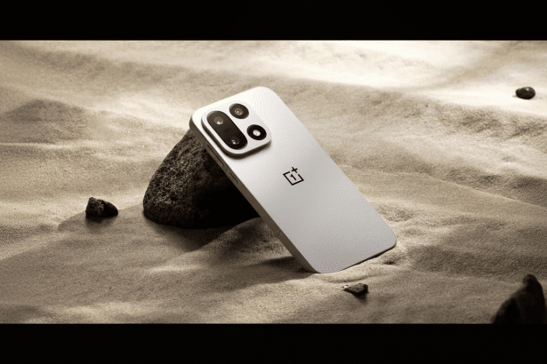 A white OnePlus smartphone rests against a dark rock on sandy ground , showcasing its camera module and logo.