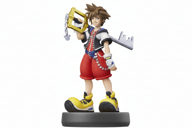 An Ami ibo figure of Sora from Kingdom Hearts, standing on a grey base, holding his Keyblade, against a white background. Filename : sora amiibo1 6x 9. png