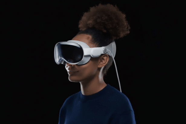 A person with dark, curly hair tied up , wearing a white virtual reality headset with a dark visor. The person is looking slightly to the right with a subtle smile. A white cable extends from the headset. The background is completely black, providing a stark contrast to the subject .