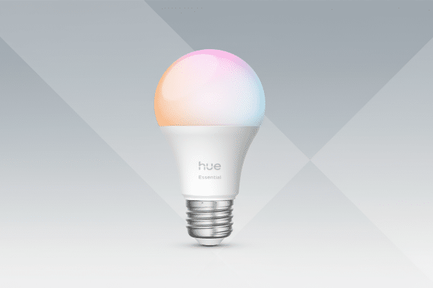 A professional 16:9 aspect ratio image of a Philips Hue Essential smart light bulb with a gradient of pastel colors on the bulb , set against a clean grey background with subtle geometric patterns. Filename : phil ipshue essentialsmart bulb1 69. png