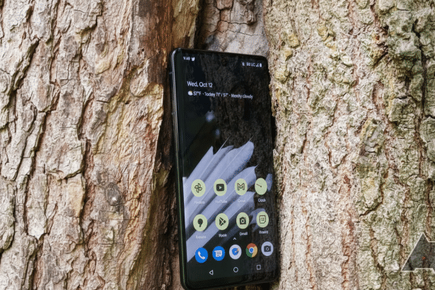 A black smartphone with a weather widget showing Wed, Oct 12 and 57° F - Today 71 ° / 57° - Mostly cloudy on its screen, resting against the textured