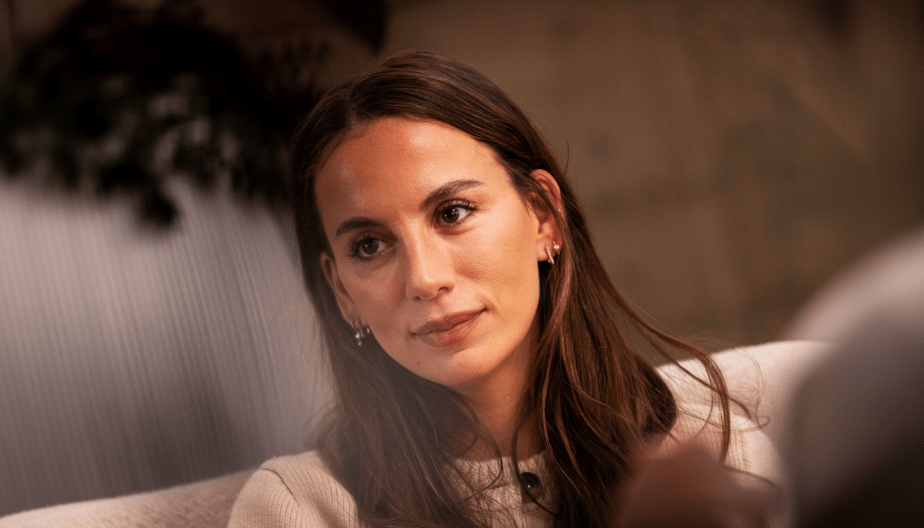 A professional head shot of a woman with long brown hair, wearing a cream - colored sweater, looking slightly to the side.