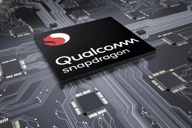 A black Qualcomm Snapdragon chip with a red and white logo , set on a dark circuit board with various other smaller chips and intricate silver trac ings. The image is professionally enhanced and resized to a 16 :9 aspect ratio , maintaining the original background.