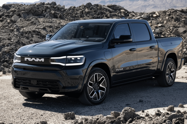 A dark grey RAM truck parked on a rocky, uneven terrain with a mountain range in the background, enhanced and resized to a 16: 9 aspect ratio.