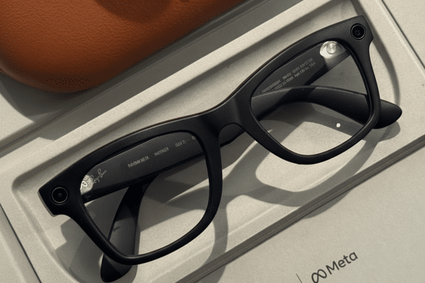 Black Ray-Ban Meta smart glasses resting on a light gray display stand , with a brown leather case partially visible in the background and the Meta logo in the bottom right.