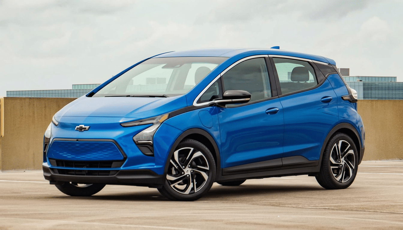 A blue Chevrolet Bolt EV parked on a concrete rooftop with buildings in the background under a cloudy sky.
