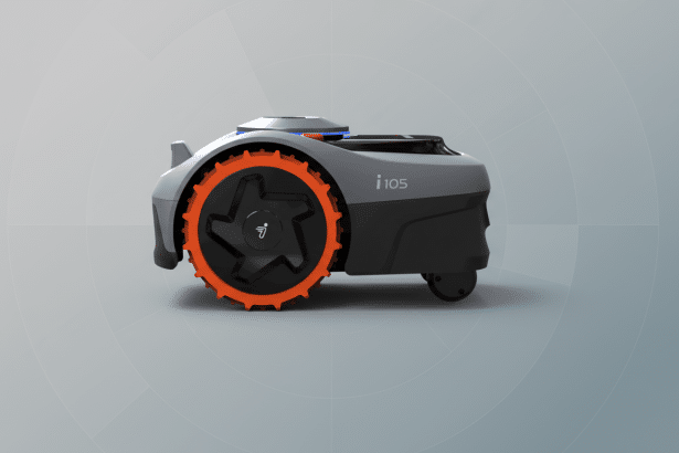A robotic lawnmower with grey housing and an orange wheel, on a subtle grey gradient background with faint circular patterns.