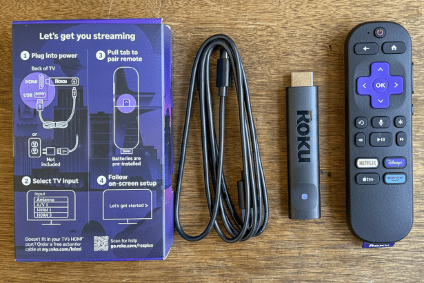 A professional overhead shot of a Roku streaming stick, remote control , and setup guide on a wooden surface.
