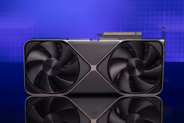 ** A dark grey graphics card with two large fans sits on a reflective surface against a blue grid background. **