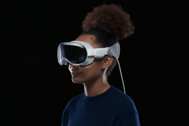 A person with dark skin and curly hair tied up , wearing a white virtual reality headset against a solid black background.