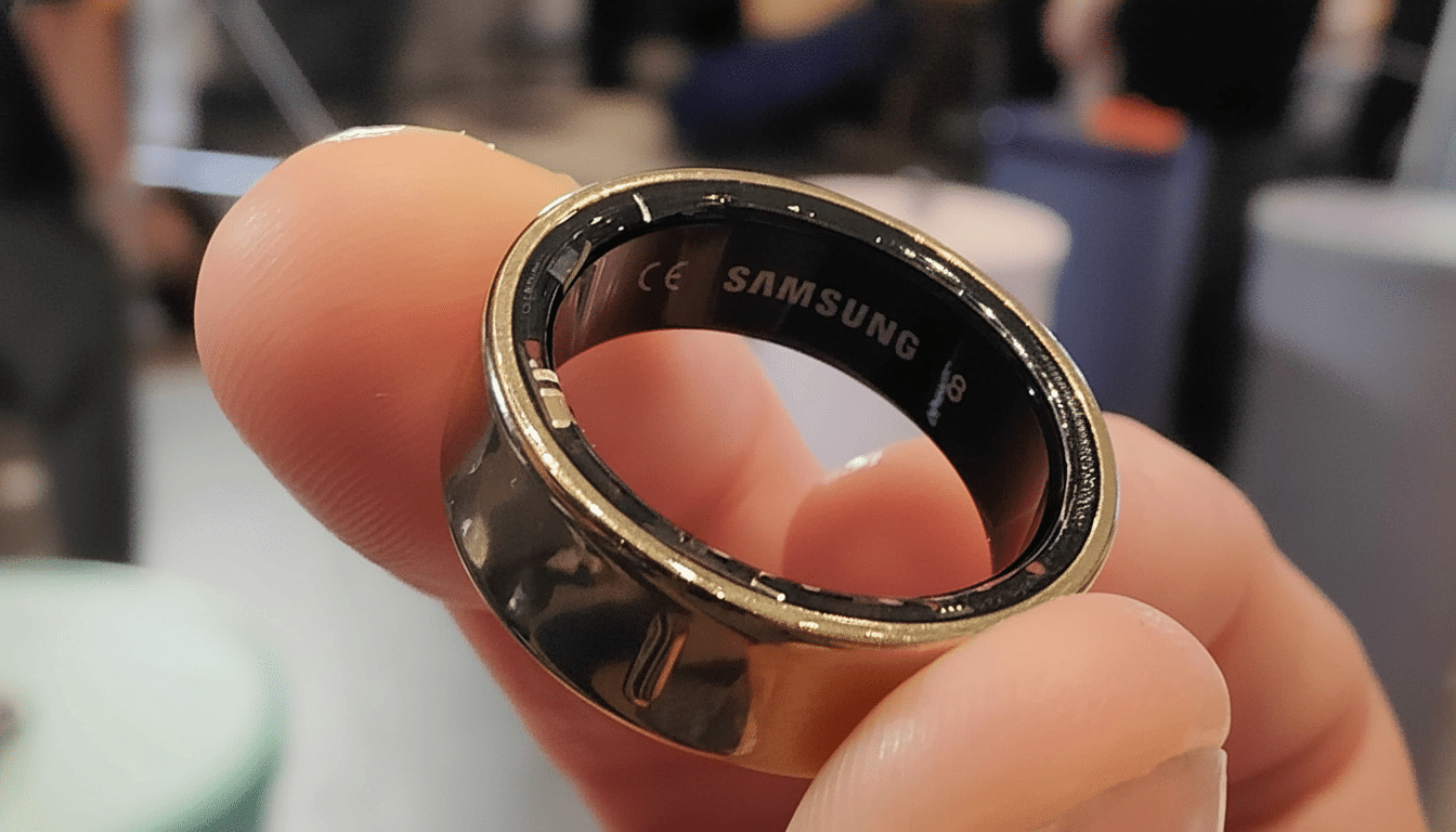 A close -up shot of a gold -colored Samsung smart ring held between two fingers, displaying the brand name and CE marking on its inner black surface.