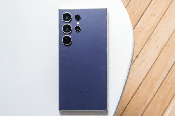 A professional overhead shot of a dark purple Samsung smartphone with multiple camera lenses, placed on a white and wooden surface, resized to a 16: 9