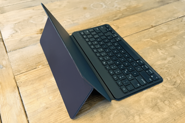 An angled view of a black tablet keyboard case with a dark blue cover, resting on a rustic wooden surface.