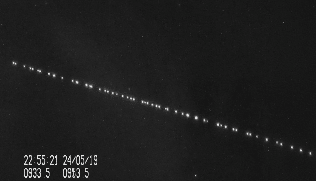 A professional , enhanced image showing a diagonal line of bright, evenly spaced lights against a dark background , likely indicating satellites in orbit. A timestamp and other numerical data are visible in the bottom left corner.