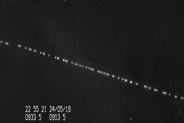 A black and white image showing a diagonal line of bright dots , likely satellites , against a dark sky with faint stars. A timestamp 22:5 5:21 24/ 05/1 9 and other numbers 0933 .5 0 953. 5 are visible in the bottom left corner. Filename : satellite trail night sky .png