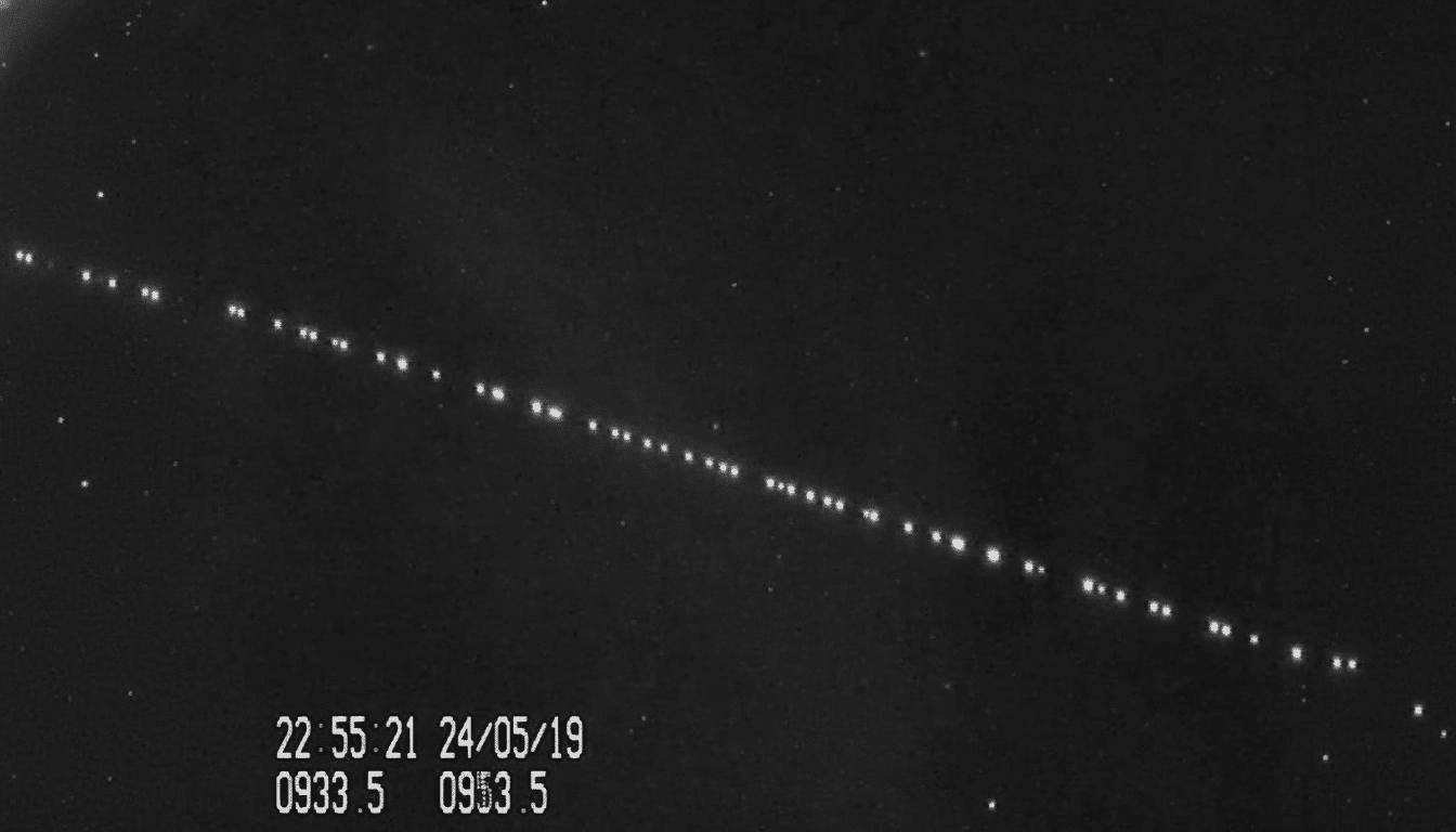 A black and white image showing a diagonal line of bright dots , likely satellites , against a dark sky with faint stars. A timestamp 22:5 5:21 24/ 05/1 9 and other numbers 0933 .5 0 953. 5 are visible in the bottom left corner. Filename : satellite trail night sky .png