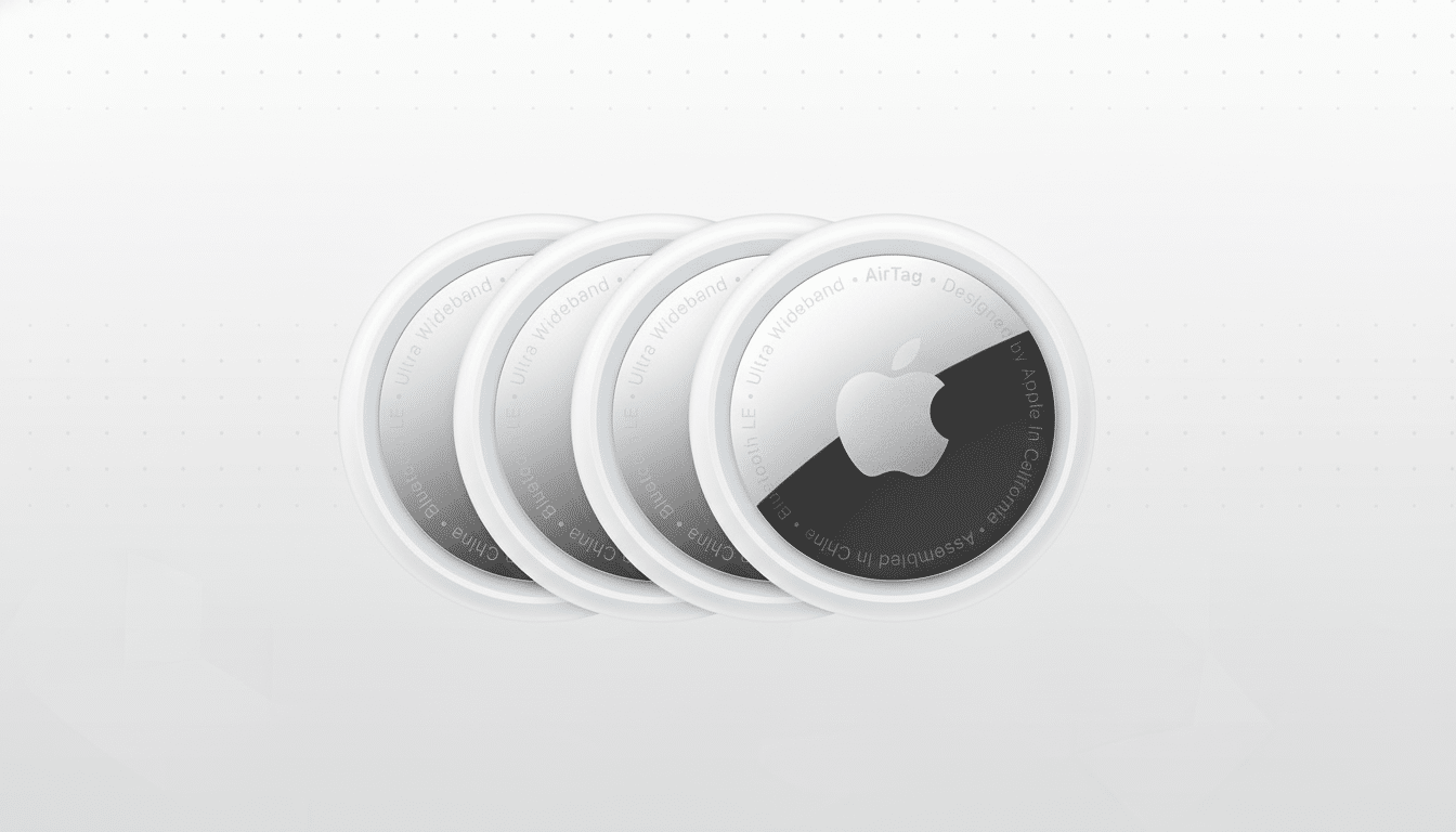 Four Apple AirTags are arranged in a row against a professional flat white background with a subtle, soft grey grid pattern. The AirTags are circular , white on the outside, with a metallic silver center featuring the Apple logo and text around the edge. Filename : fourapple airtags professional. png