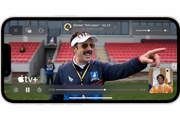 An iPhone displaying a 1 6:9 aspect ratio video of Ted Lasso on Apple TV+, with a small picture - in-picture video call overlay and controls .