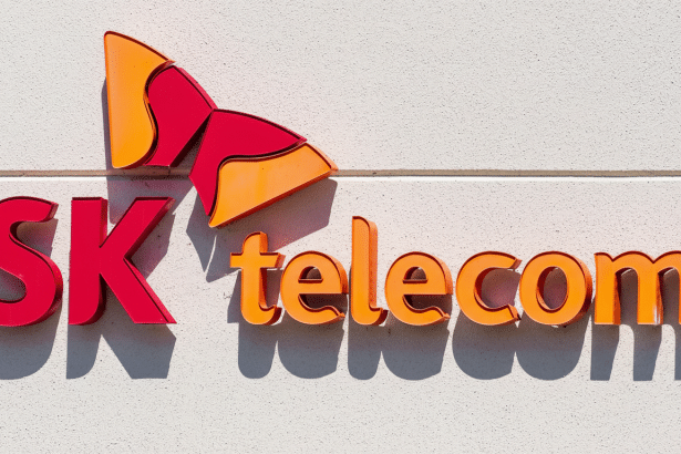 The SK Telecom logo, featuring the company name in red and orange 3D lettering , mounted on a white textured wall, presented in a 1 6:9 aspect ratio. Filename : sktele comlogo 169 . png