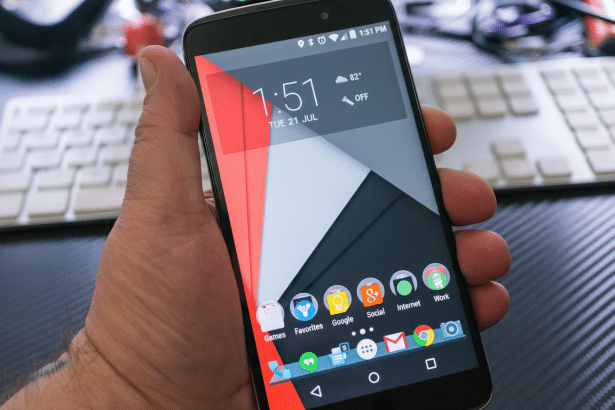 A hand holding a smartphone displaying the home screen with various app icons, time, and weather.