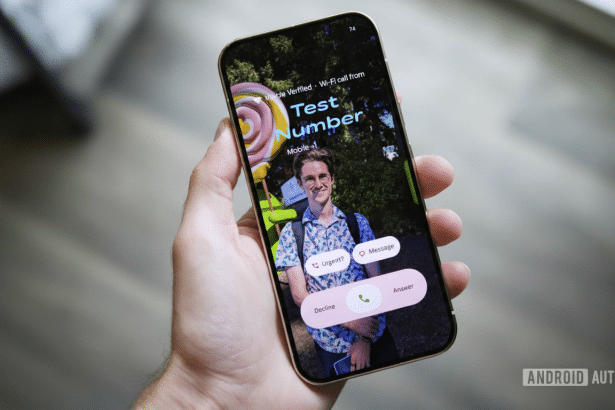 A hand holding a smartphone displaying an incoming call from Test Number with a photo of a man in the background, set against a blurry indoor background. Filename : smartphone incomingcall .png