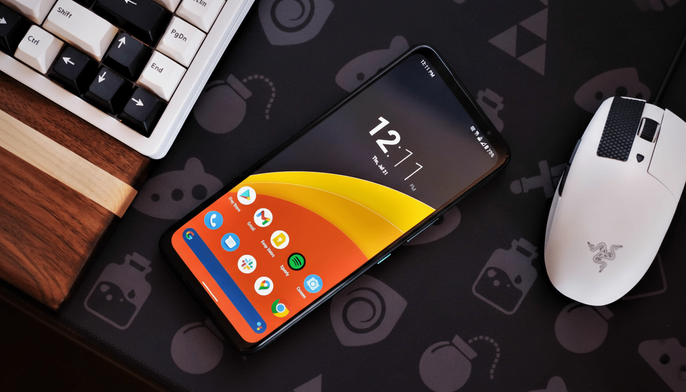 A smartphone displaying the time 1 2: 11 PM on a black mat with a white keyboard and mouse.