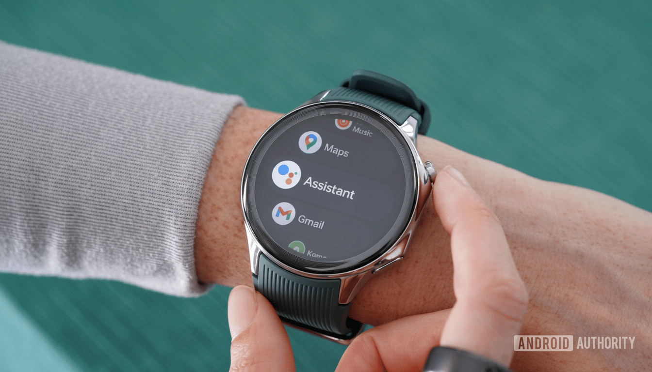 A person ' s wrist wearing a dark green smartwatch with a round display showing app icons for Music, Maps, Assistant, and Gmail .