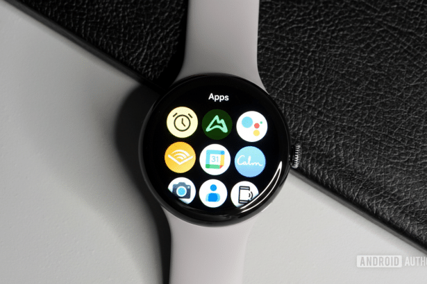 A top -down view of a light grey smartwatch with a black circular display showing various app icons. Filename : smartwatch apps display .png