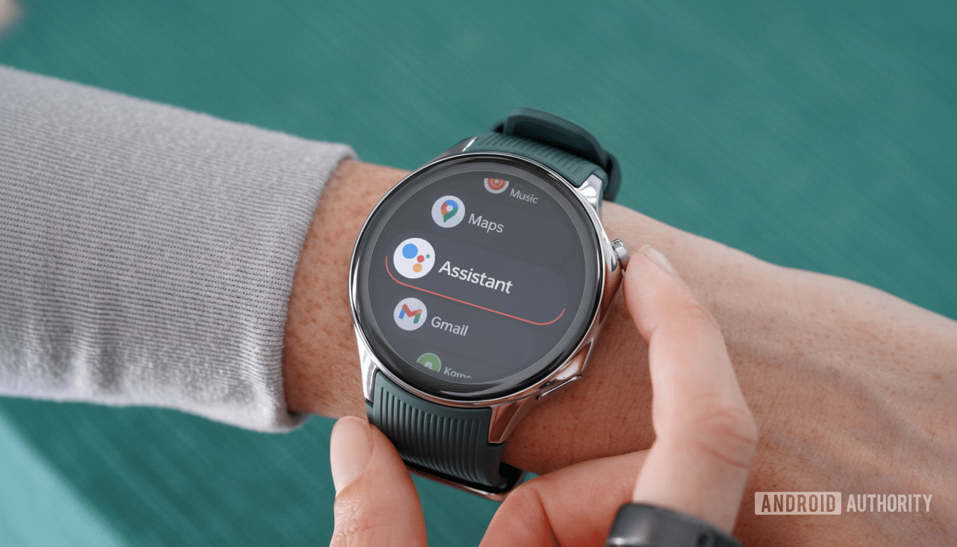 A professional shot of a smartwatch on a persons wrist, displaying app icons for Music, Maps, Assistant, and Gmail on its screen. The background is a