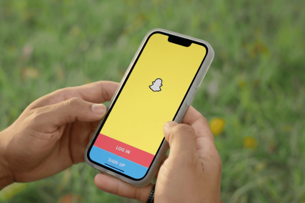 A person holding a smartphone displaying the Snapchat login screen with a grassy background. Filename : snapchat loginscreen 169 .png