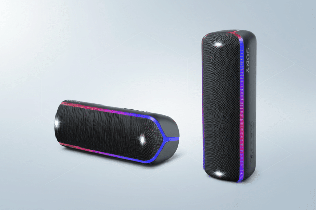 A professional shot of two Sony bluetooth speakers, one horizontal and one vertical, with their colorful LED lights on, set against a subtle gradient