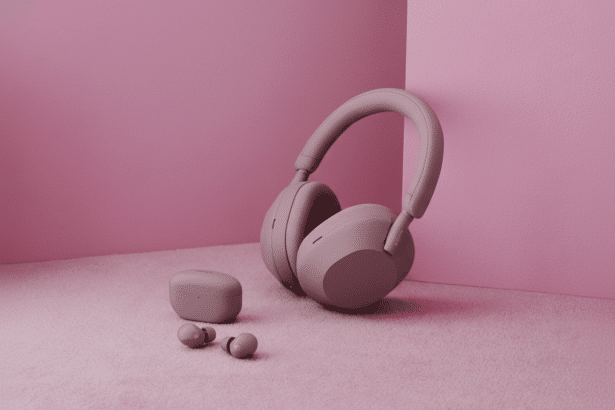 Pink Sony over -ear headphones, matching earbuds, and their charging case are arranged on a pink textured surface against a pink background, presented