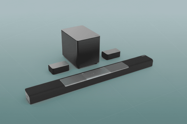 A modern black soundbar with two small satellite speakers and a subwoofer , presented on a subtle light blue gradient background with a faint grid pattern .