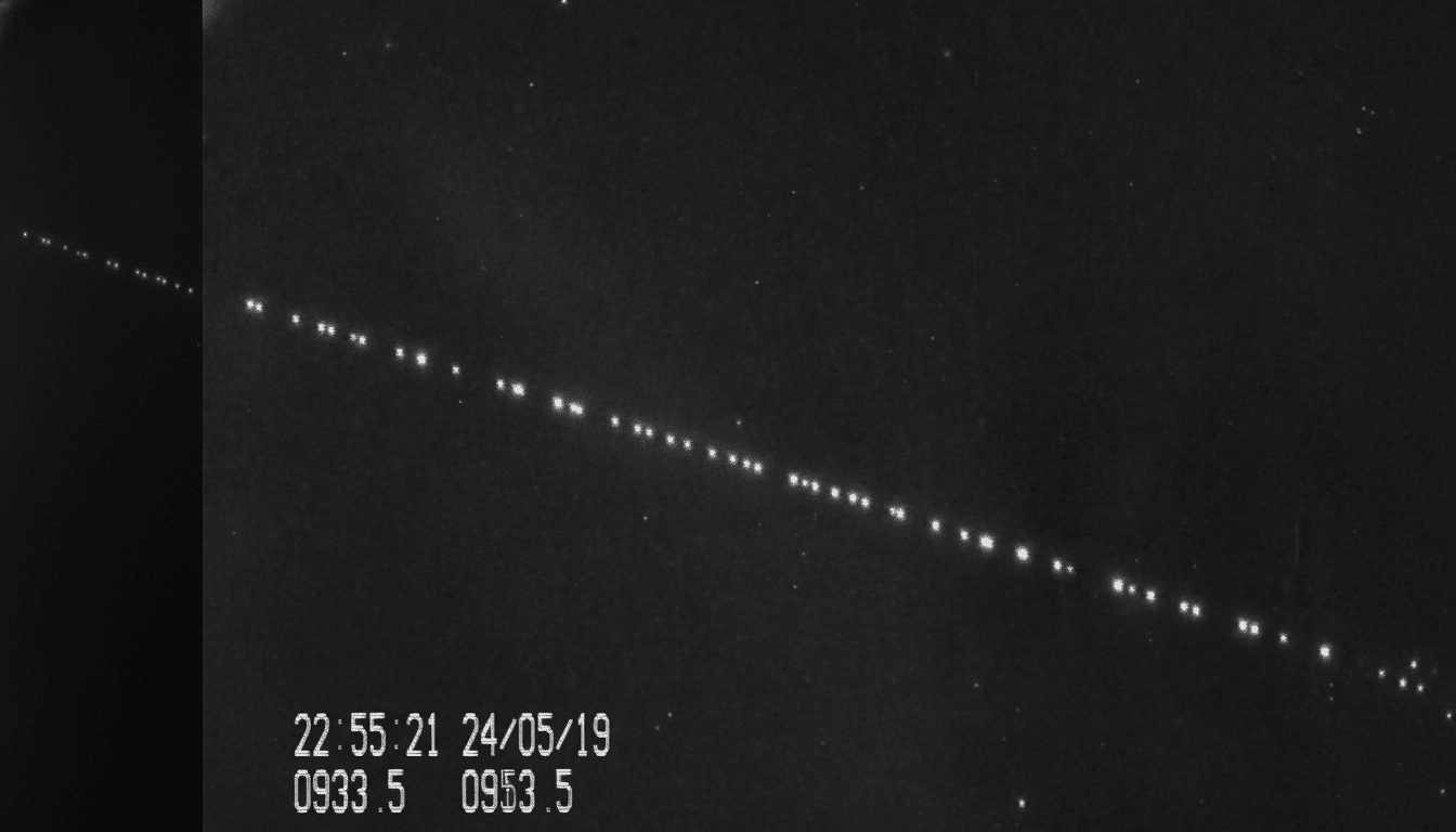 A professional, enhanced black and white image displaying a diagonal line of bright, evenly spaced dots against a dark background, representing a sate