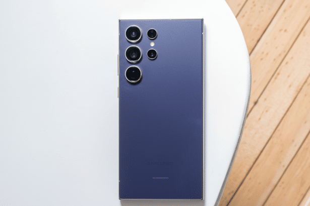 A professional overhead shot of a dark purple Samsung smartphone with multiple camera lenses , presented on a white and wooden surface, resized to a 16:9 aspect ratio.
