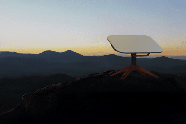 A Star link dish on a rocky outcrop against a mountain range at sunset. Filename : starlink dishsunset mountains.png