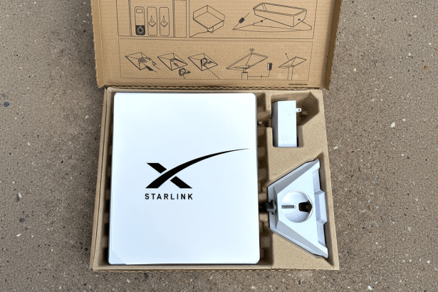 An open Starlink box revealing the white Star link router , power adapter, and stand , all nestled in their cardboard compartments .