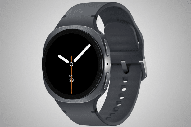 A professional shot of a dark gray smartwatch with a black circular display showing SAT 28 and white clock hands, set against a subtle gray gradient background.