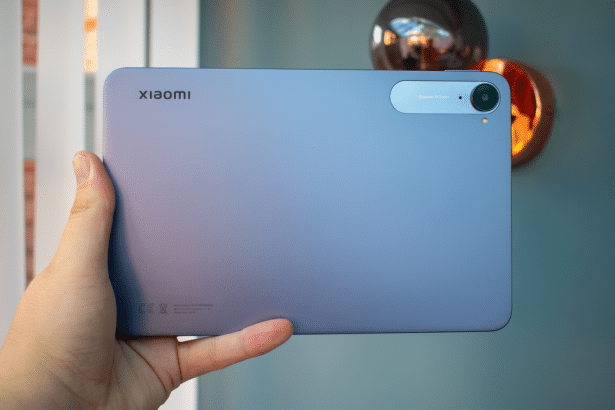 A hand holding a purple Xiaomi tablet, with the camera and brand logo visible, presented in a 16:9 aspect ratio.