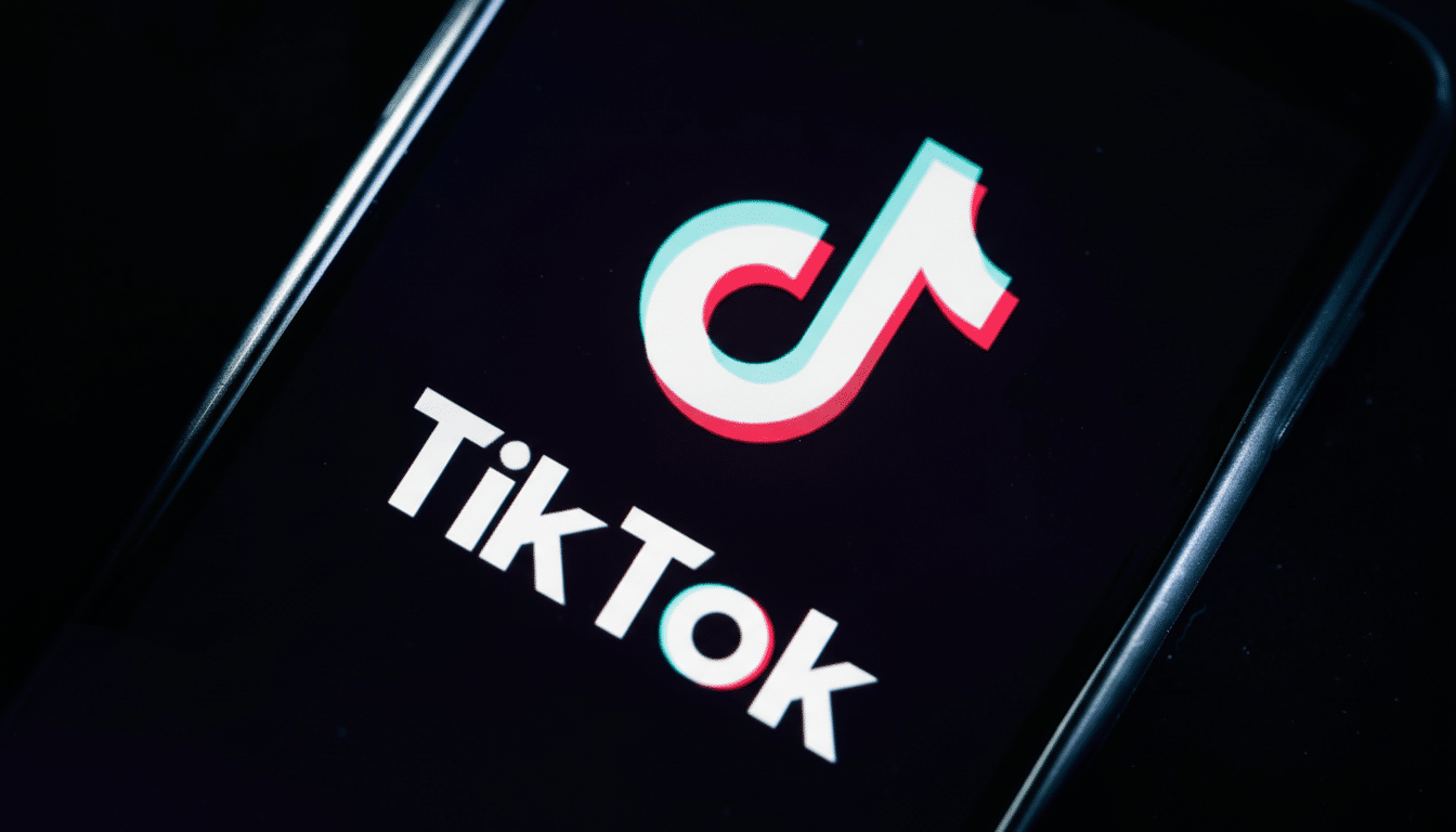 The TikTok logo and word mark displayed on a smartphone screen, with the iconic white, red, and blue musical note icon and white text on a black backg